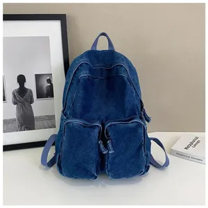 Detailed view of the retro blue denim backpack featuring dual front pockets and top handle.