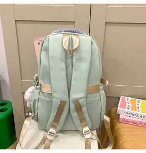 Mochila escolar verde claro con correas doradas y colgante de peluche, estilo para estudiantes.