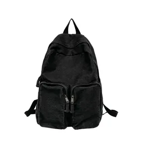Detailed view of the black denim backpack, showing the front dual zipper pockets and fabric.