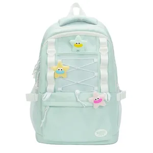 Dettaglio zaino verde menta con design multi-tasche, spalline bianche e ciondoli a stella in peluche.