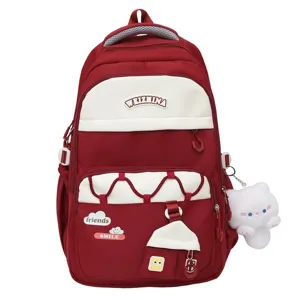 Detalles de la mochila escolar roja y blanca con colgante de gato de peluche y bolsillos multiples.