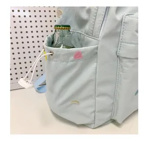 Λεπτομερές κοντινό πλάνο της πλαϊνής τσάντας γαλάζιου σακιδίου με κεντήματα.