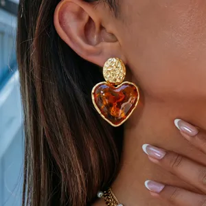 Detailed closeup view of the elegant amber heart earrings with textured gold metal finish.