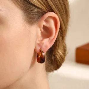 Close-up detail shot of vintage brown resin hoop earrings worn on ear, elegant and chic.