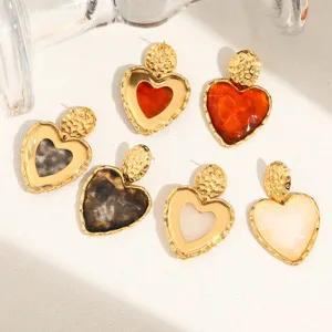 Detailed close-up shot of heart-shaped stainless steel stud earrings in various colors.