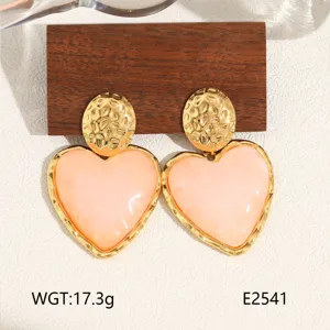 Detailed view of trendy gold-plated titanium steel heart earrings with chic pink resin drop.