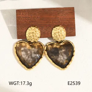 Close-up of gold hammered and translucent resin heart drop earrings, elegant design.