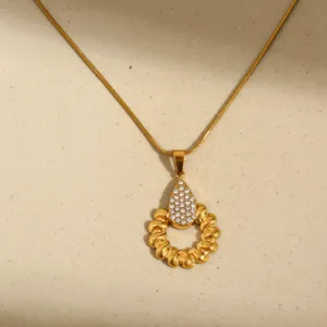 Collar de acero inoxidable dorado con lágrima de cristal y colgante de anillo retorcido.