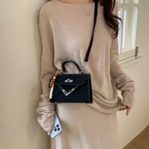 Chic black women's crossbody bag with elegant turn-lock closure and cute beaded charm detail.