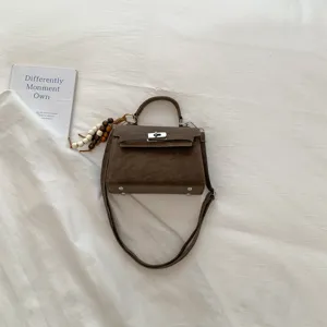 Stylish brown leather top handle handbag with metal lock and shoulder strap for women daily use.