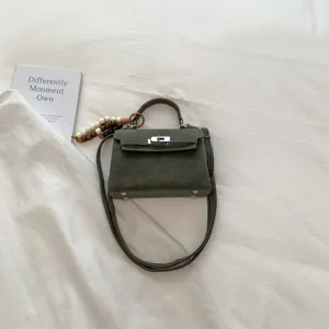 Dark green mini Kelly handbag, chic top handle crossbody bag with lock closure and charm.
