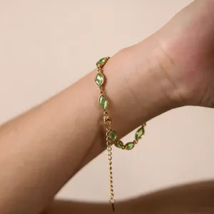 Primo piano dettaglio del bracciale in acciaio inossidabile oro 18k con pietra verde.