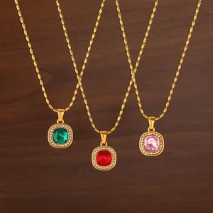 Detailed view of three elegant gold-tone necklaces with square crystal stone pendants.