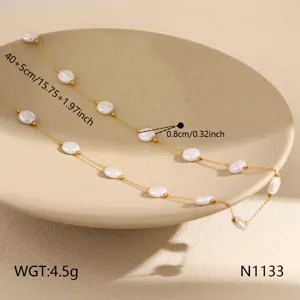 Pearl necklace detail shot, delicate gold chain with flat white beads, close-up view.