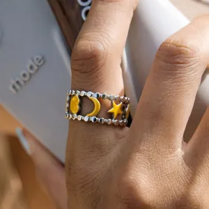 Stainless steel celestial ring detail showing yellow cloud, moon, and star enamel designs.