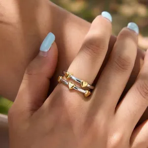 Detailed close-up shot of the stacked heart rings featuring gold-colored metal hearts on bands.