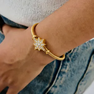 Detailopname van de elegante gouden kabelmanchetarmband met fonkelende strass-sterrenhanger.
