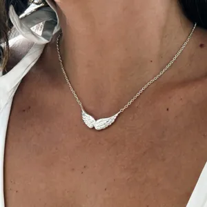 Close-up detail shot of dainty silver-tone angel wing pendant necklace on delicate chain.