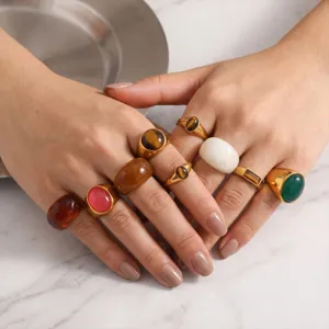 Closeup detail of trendy stainless steel chunky rings with colorful stones worn on hands.