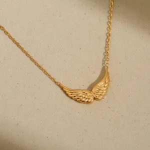 Detailed shot of gold-colored angel wing pendant necklace, elegant metal clavicle chain.