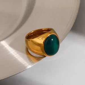 Detailed shot of a stylish gold stainless steel ring with a deep green gemstone, chic aesthetic.