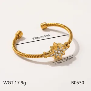Detailopname van de gouden roestvrijstalen kabelarmband met fonkelende kristallen ster.