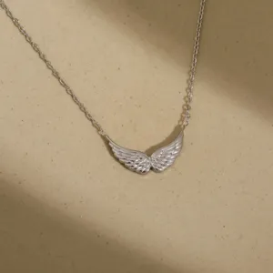 Silver angel wing pendant necklace detail close up shot, delicate clavicle chain jewelry.