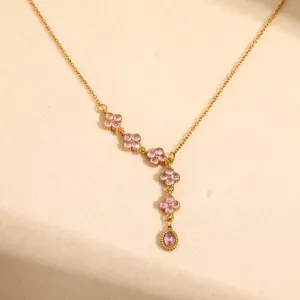 Detail view of a gold titanium steel necklace featuring delicate pink flower cubic zirconia charms.