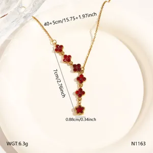 Detail view of gold stainless steel necklace with red crystal clover motifs and star pendant.
