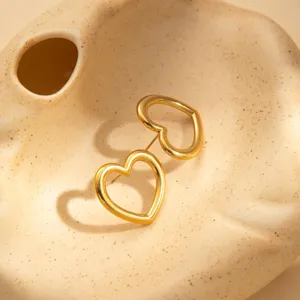 Close-up detail of stylish hollow gold heart earrings displayed on a chic ceramic tray.