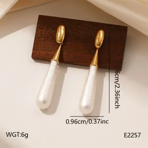 Long drop teardrop earrings with gold-toned metal and white textured pendant, detail view.