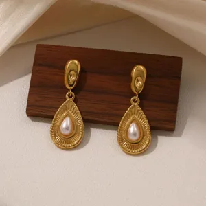 Detail shot of vintage gold teardrop pearl earrings showcasing delicate texture and elegant design.
