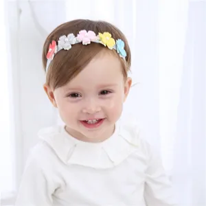 Gros plan détail du joli bandeau bébé avec fleurs en tissu colorées et perles au centre.