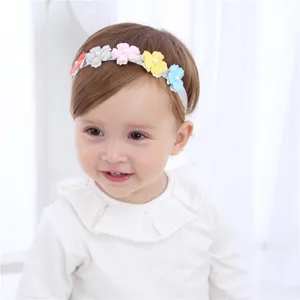 Détail de bandeau bébé mignon avec fleurs en tissu coloré et perles pour les nourrissons.