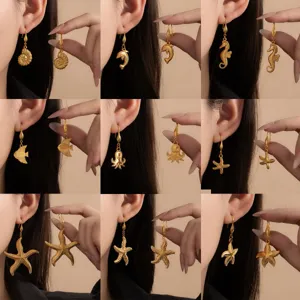 Gold ocean theme earrings detail featuring starfish, seahorse, and shell designs close-up.