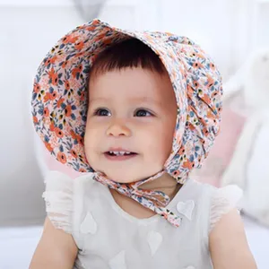 Baby zonnehoed van katoen met bloemenprint en kinbandjes, zacht en comfortabel.