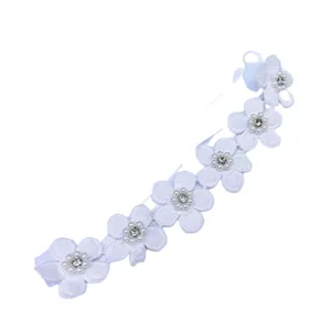 Close-up van de witte babyhaarband met parels en strass in een zoet bloemenkantontwerp detail.