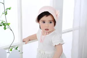 Schattige roze baby emmerhoed van opengewerkt kant met mooie bloemversiering en handig koord.