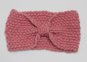 Pink knitted winter headband with twist bow design, soft and warm hair accessory detail.