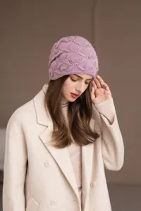 Primo piano dell'elegante berretto in maglia rosa con delicati dettagli di perle.