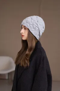 Primo piano elegante berretto in maglia grigio chiaro con perle, caldo e morbido.