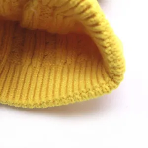 Close-up of a bright yellow baby knitted woolen hat with detailed ribbed texture design.