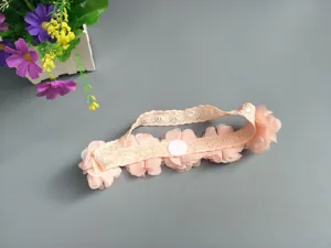 Pink floral baby headband with delicate lace design, perfect detail view for photo props.