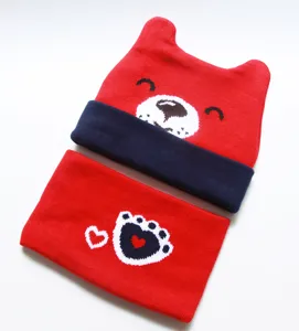 Infant knitted hat and scarf set with cute bear ears and heart paw design for cold weather.