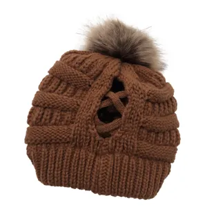 Nahaufnahme Detail der braunen Winter Strickmütze mit Zopföffnung und flauschigem Bommel.