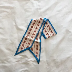 Gros plan détail du foulard twilly en soie mince de style coréen avec bordure bleue.
