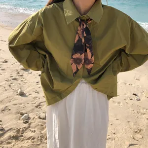 Vue détaillée d'un foulard en soie à motif floral rétro noué élégant autour du cou.
