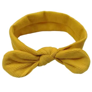 Vista dettagliata della fascia per neonati in maglia gialla con un grazioso fiocco annodato.