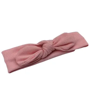 Dettaglio fascia per capelli neonata in maglia rosa, soffice accessorio con fiocco per piccoli bimbi.