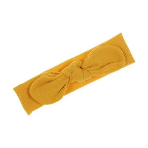 Primo piano della fascia per neonati gialla a costine con un fiocco, morbido per neonati.